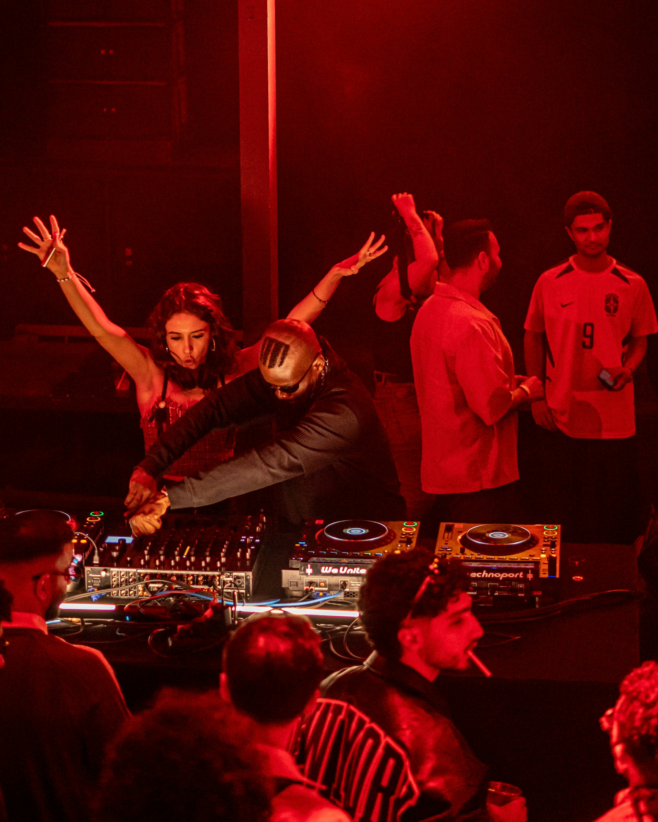 Foule réunie autour d’un DJ dans une lumière rouge